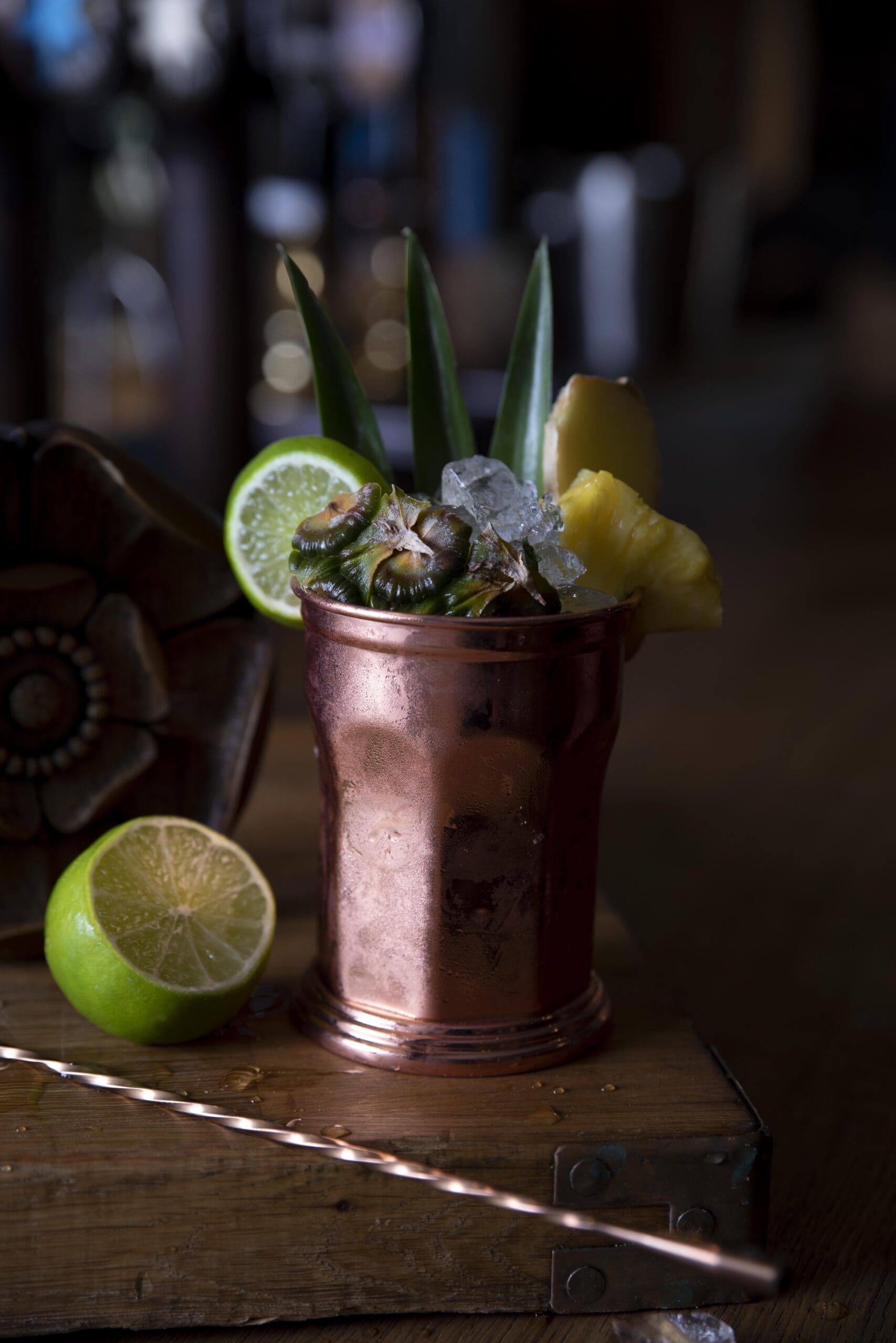 Spiced Pineapple and Ginger Rum Mojito on a wooden table, night time background with lime.